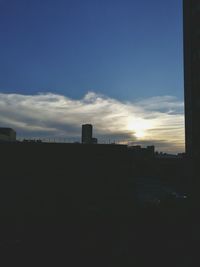 Silhouette of buildings against cloudy sky