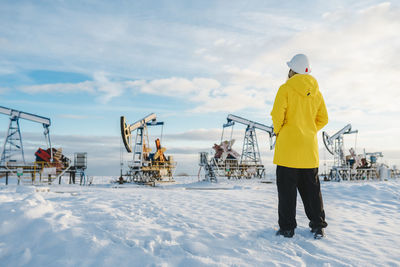 Young engineer standing at oil production field in winter