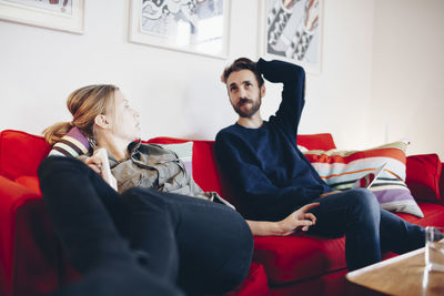 Couple talking while relaxing on sofa at home