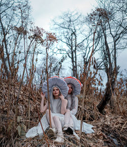 Young woman sitting on field against trees