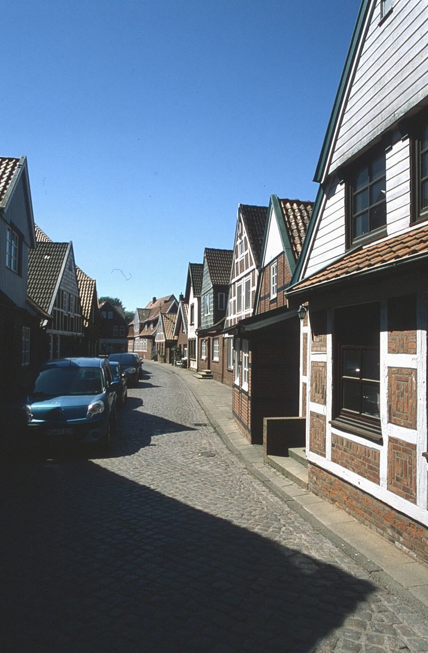 building exterior, architecture, built structure, building, sky, clear sky, motor vehicle, city, car, transportation, mode of transportation, street, nature, day, sunlight, blue, residential district, house, land vehicle, road, no people, outdoors, row house