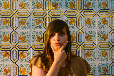 Portrait of young woman standing against wall