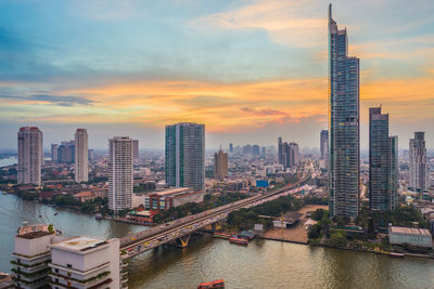 Panoramic view of river amidst buildings against sky during sunset