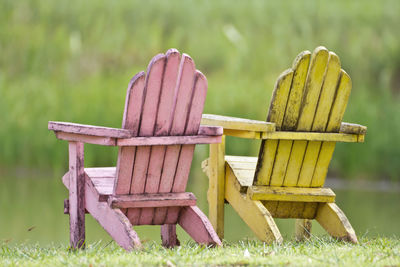 Wooden chairs on field against plants