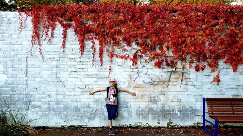 Full length of woman standing by wall