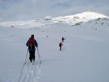 Rear view of people walking on snowcapped mountain