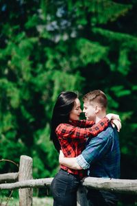 Side view of young couple standing face to face in forest