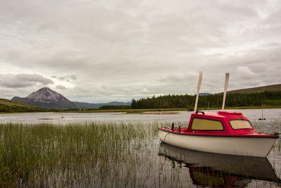 Boat moored on lake against sky