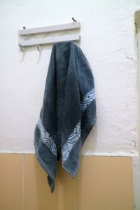 A photo of a dark blue wet towel hung on the bathroom wall