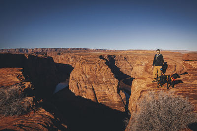 A man with a dog is standing near horseshoe bend, arizona