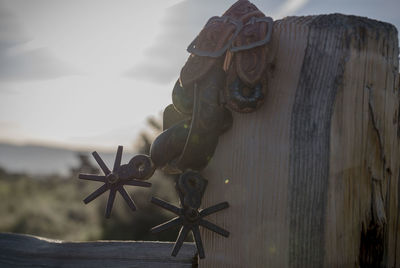 Close-up of equipment on wooden post during sunset