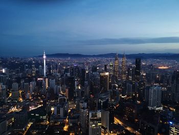 Aerial view of city lit up against sky