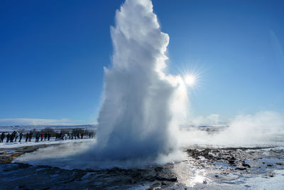 Panoramic view of people along with geyser against sky