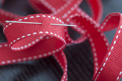 Close-up of red ribbon and sewing needle on table