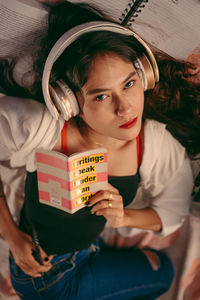 Portrait of young woman holding book at home