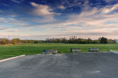 Road amidst field against sky during sunset