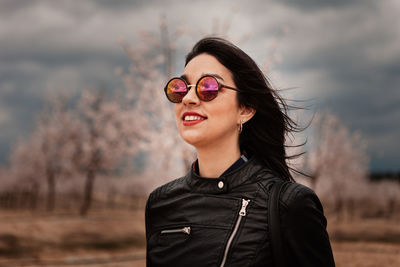 Portrait of smiling young woman standing against blurred background