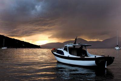Fishing boat in sea against sky during sunset