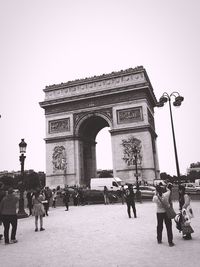 People walking in front of liberty against clear sky