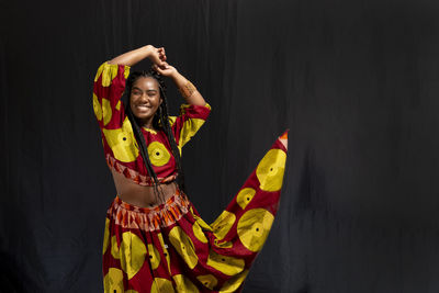 Young woman wearing colorful long clothes over black background. natural expression.