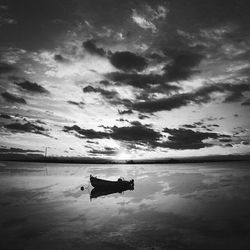 Boats in sea against cloudy sky