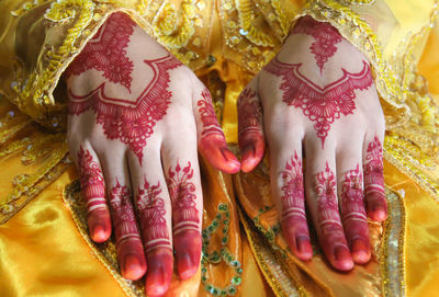 Midsection of bride showing henna tattoo during wedding ceremony