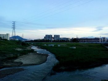 Scenic view of river by city against sky