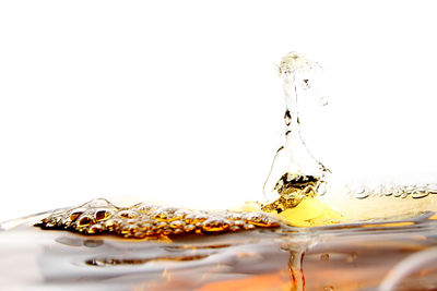 Close-up of water splashing on glass against white background