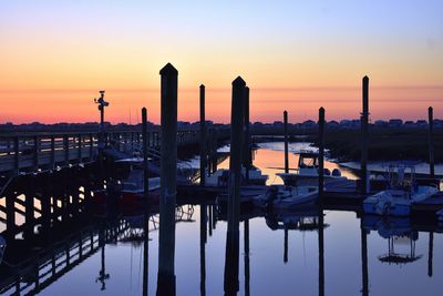 Boats moored at harbor against sky during sunset