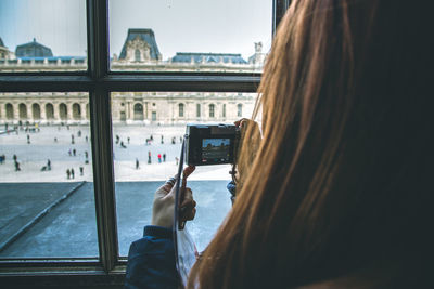 Rear view of woman photographing musee du louvre with camera