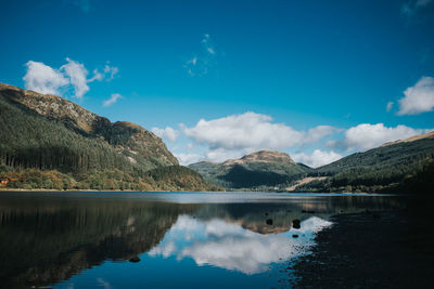 Scenic view of lake by mountains against sky