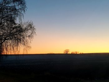 Scenic view of silhouette field against clear sky during sunset