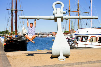 Man sailing on boat moored at harbor against clear sky