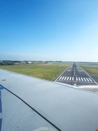 Airplane on runway against clear blue sky