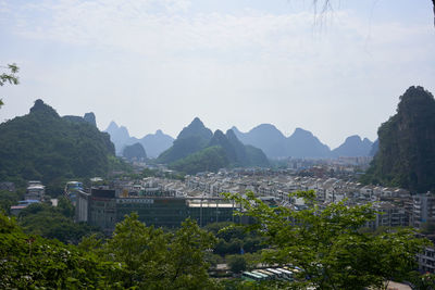 Scenic view of townscape by mountains against sky