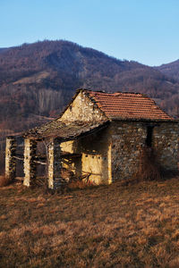 Abandoned house on field by mountains against sky