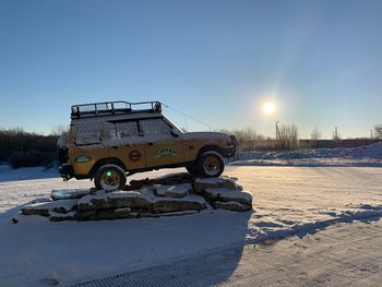 Car on snow covered field against clear sky