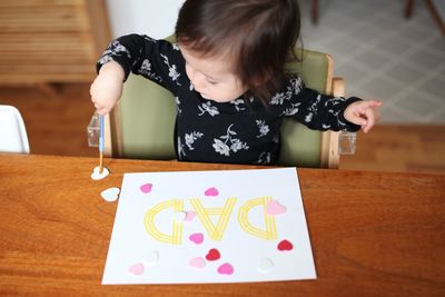 High angle view of baby girl making greeting on table during father day at home