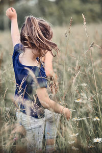 Girl standing amidst plants on field