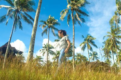 Low angle view of asian woman walking amongst palm trees