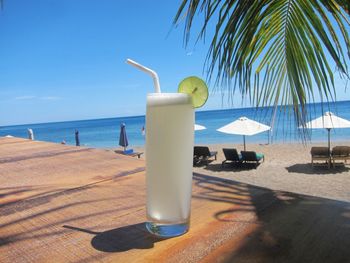 Cross on table by sea against sky