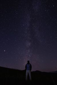 Rear view of man standing against star field at night