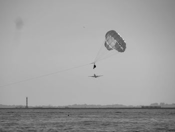 Low angle view of paragliding over sea against clear sky