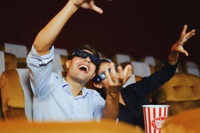 Woman holding food by man gesturing in movie theater