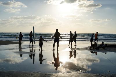 Family enjoying at beach against sky