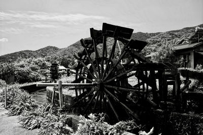 Traditional windmill on field by mountain against sky