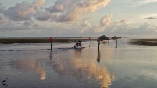 People on beach against sky during sunset