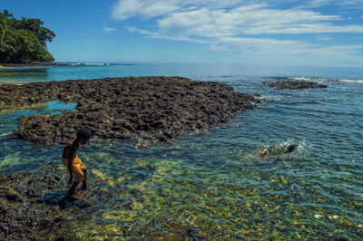 Shirtless boy standing in sea