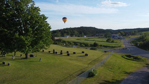 Hot air balloon flying over field against sky