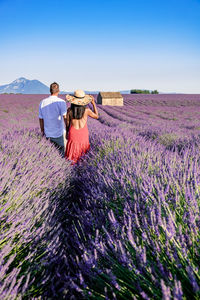 Rear view of couple on field against sky